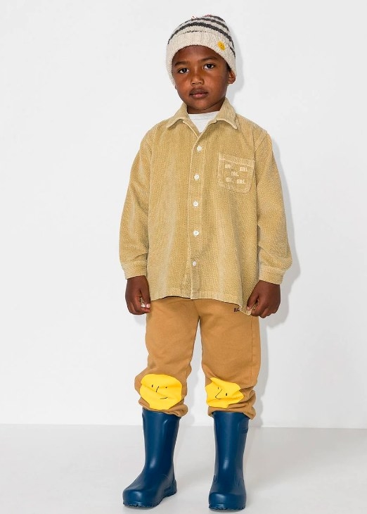 A child model wearing the corduroy button-up shirt with pants, boots, and hat