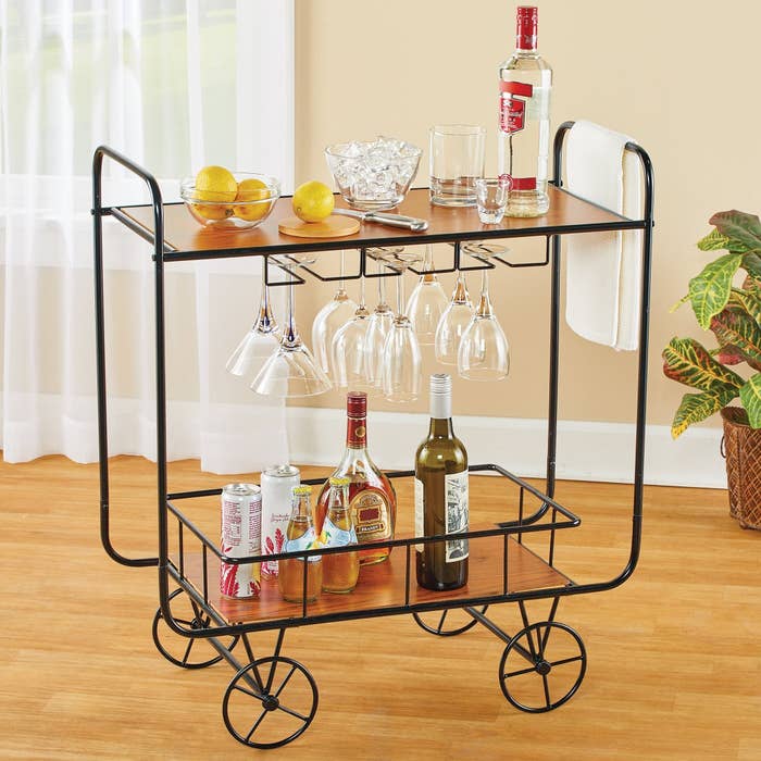 Bar cart with wheels holding alcohol, lemons, and glasses on it