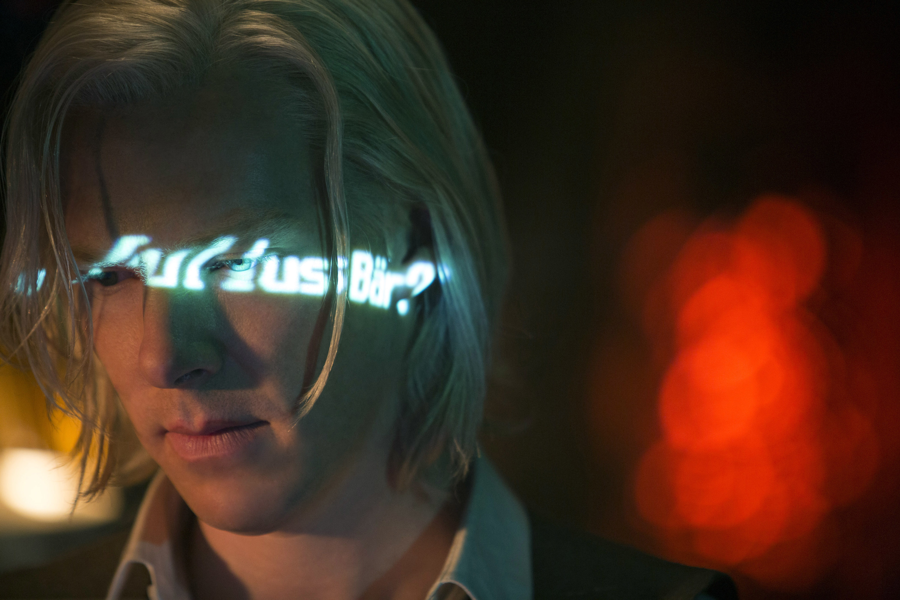 Assange hacking with text glowing on his face