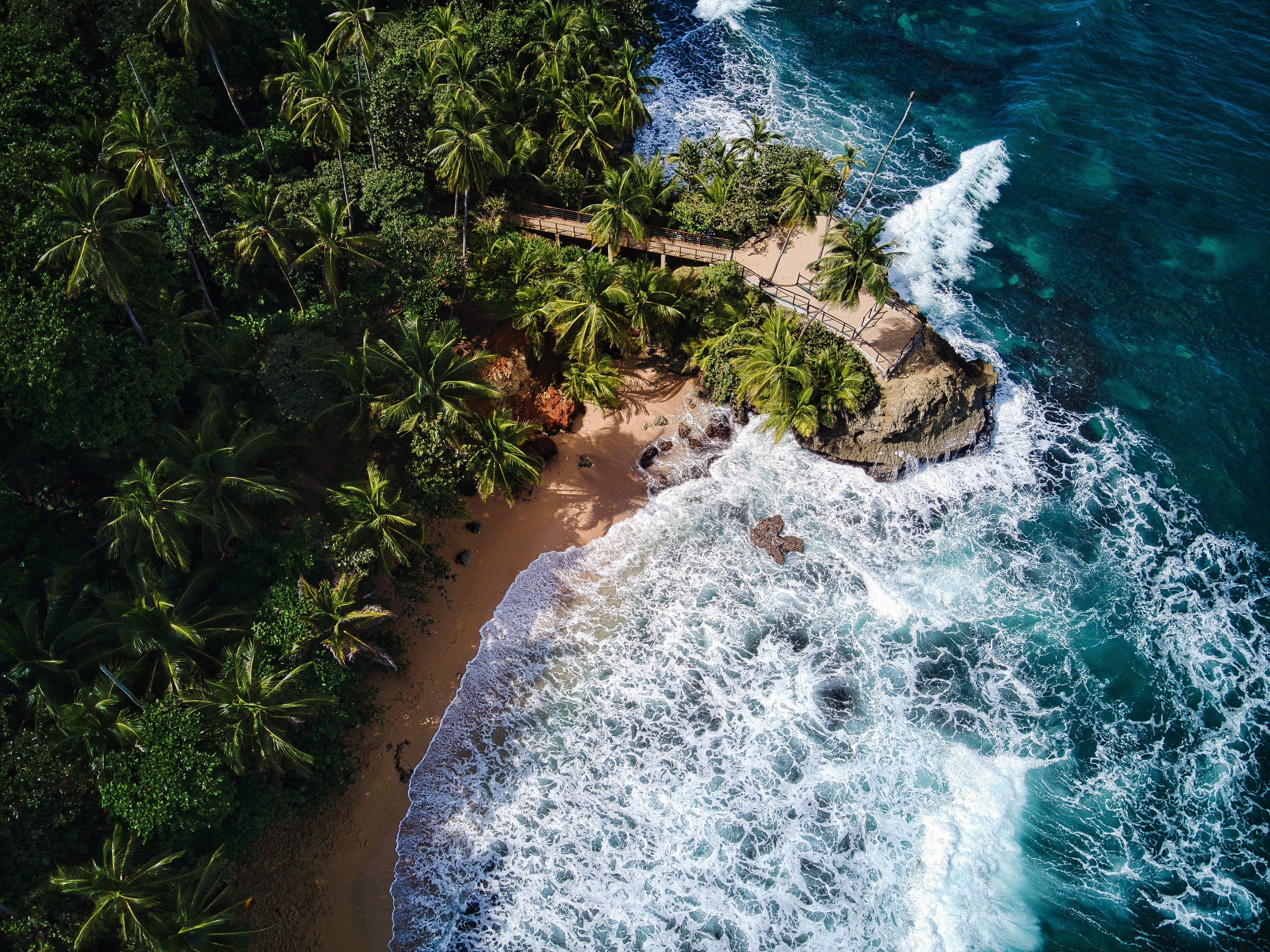 waves crashing against the shore with a jungle covered beach in Costa Rica