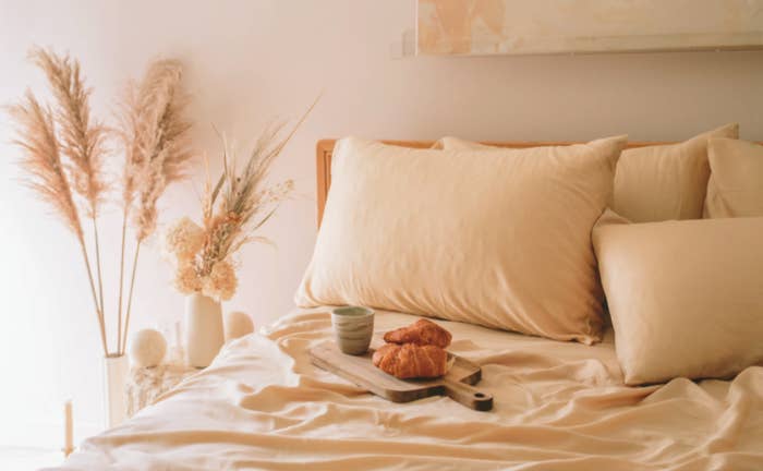 bedding styled in a bedroom with a tray of croissants and coffee on a serving platter