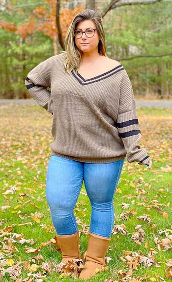 Another reviewer poses outside wearing the sweater in khaki with blue jeans and brown boots