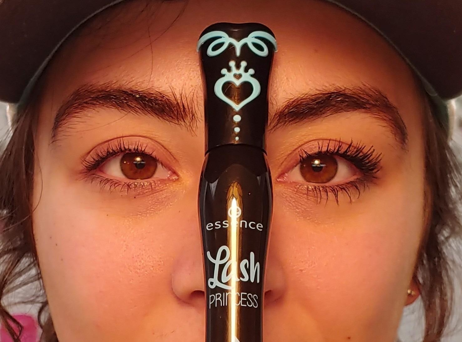 reviewer holds tube of mascara between one eye without mascara and one eye with longer, more fuller lashes after applying mascara