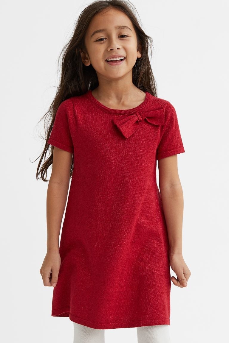 a child in a red glittery dress with a bow