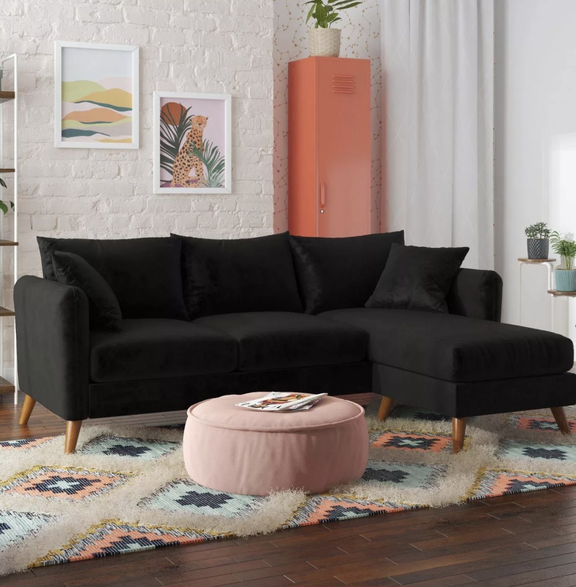The black sofa has an L shape and five pillows