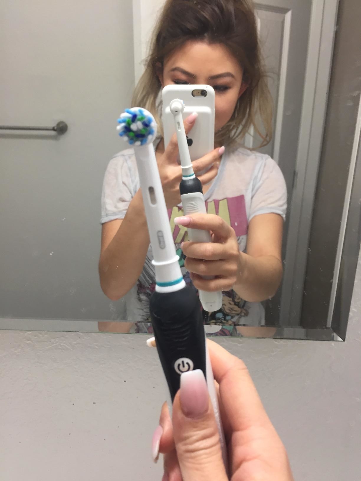 reviewer holding up black oral-b toothbrush