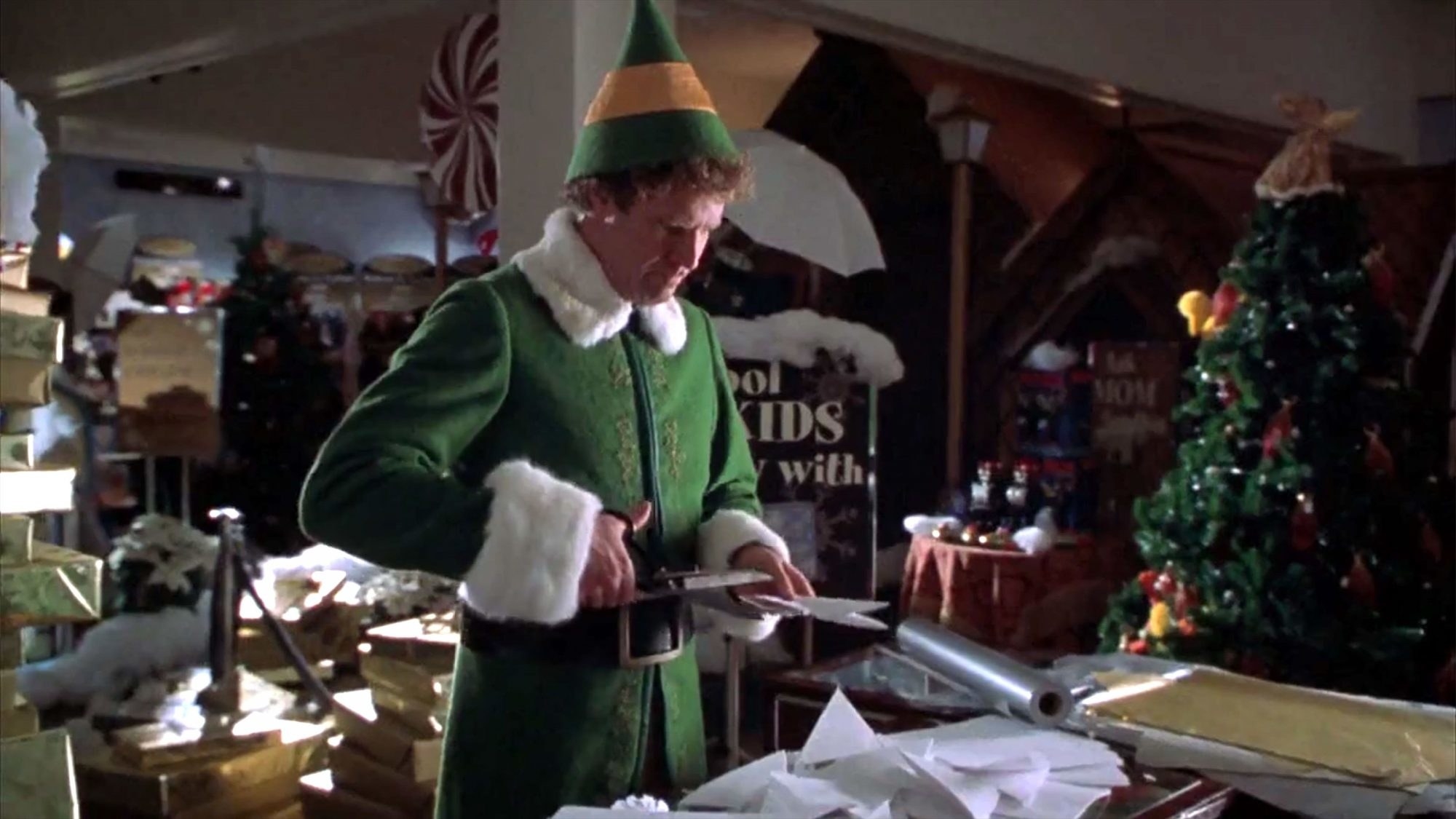 An adult elf cutting into wrapping paper