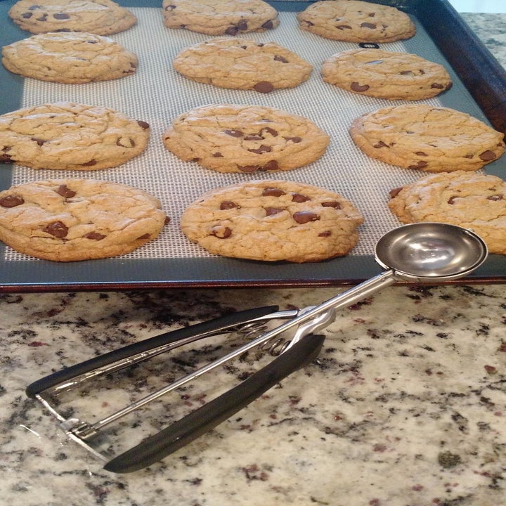 Reviewer photo of the cookie scoop next to a tray of uniformly-sized chocolate chip cookies