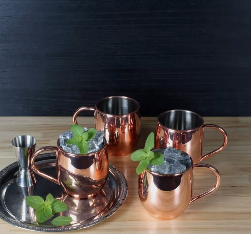 the copper mugs on a serving tray with ice and mint leaves inside