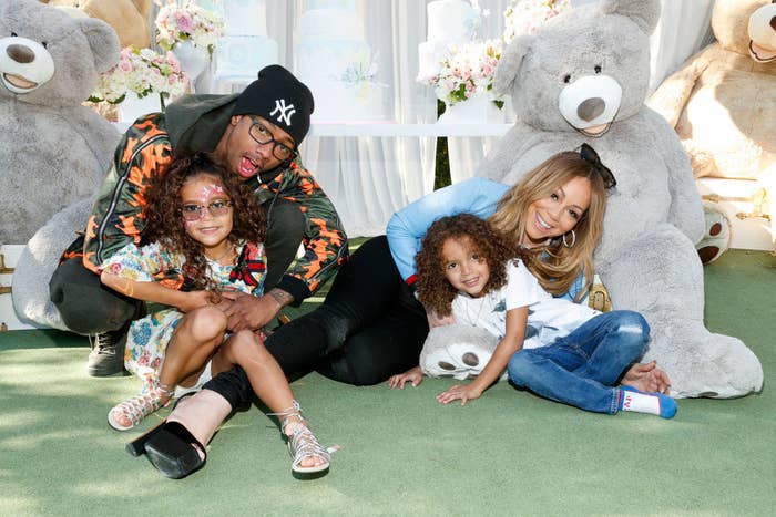 Nick Cannon posing for a photo on the ground with Mariah Carey and their two children Moroccan and Monroe