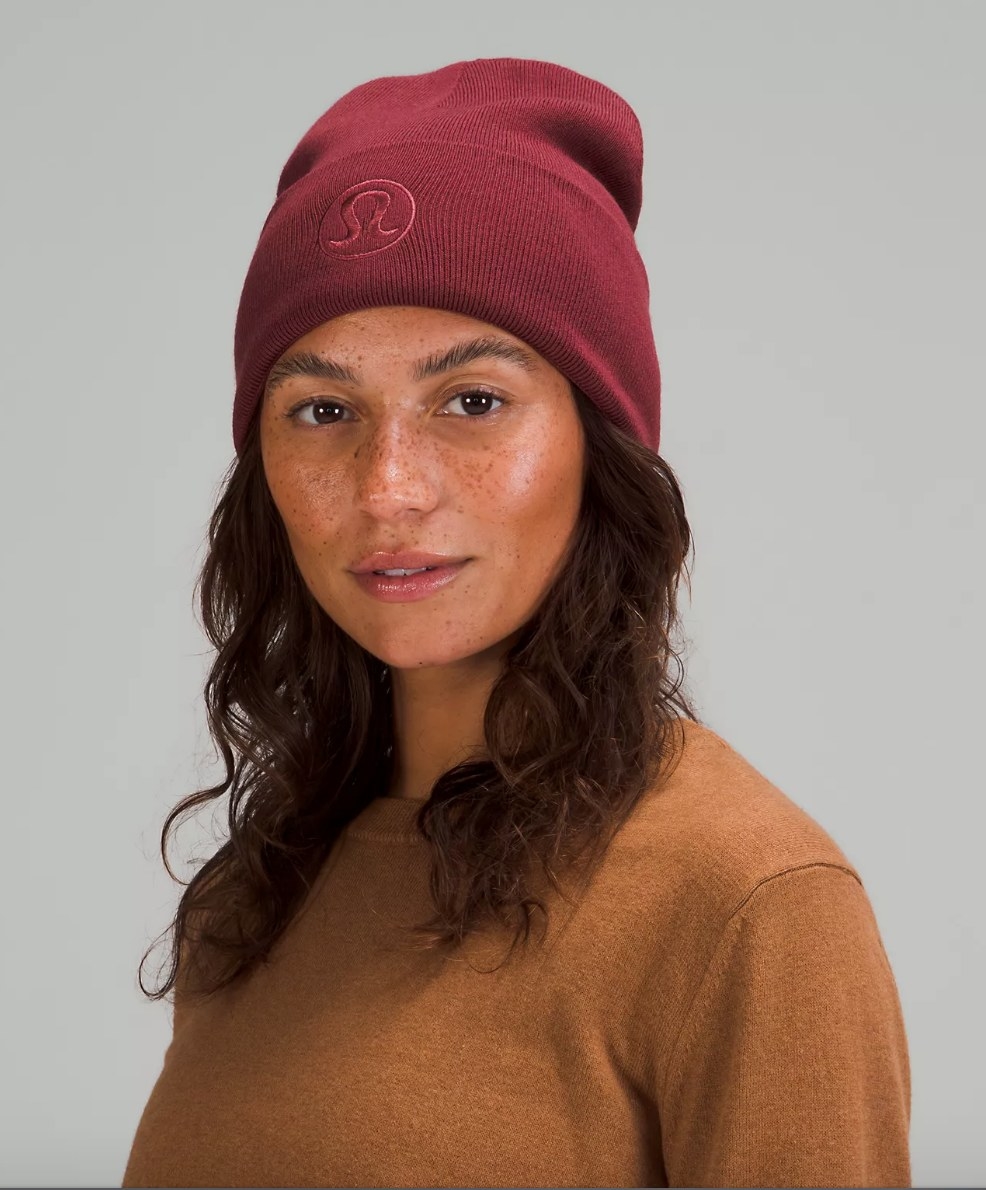 Model wearing deep red beanie with Lululemon embroidered logo on front
