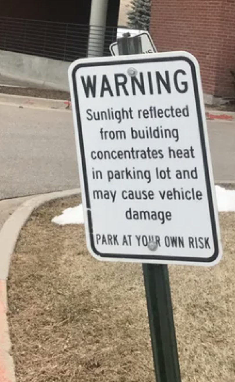 Sign: &quot;Sunlight reflected from building concentrates heat in parking lot and may cause vehicle damage&quot;
