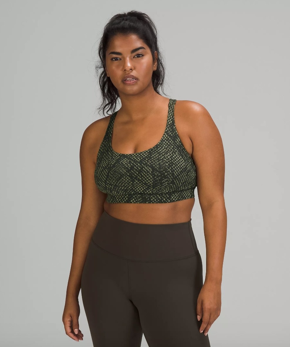 Model wearing green reptilian skin design sports bra with brown leggings