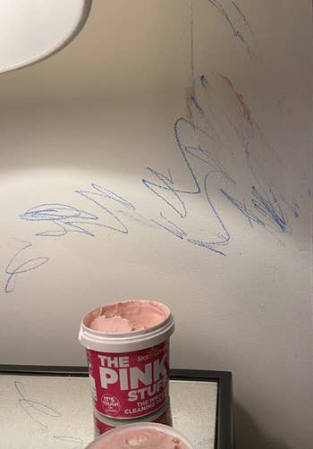 A customer reviewer's before photo which shows a white wall covered in crayon scribbles