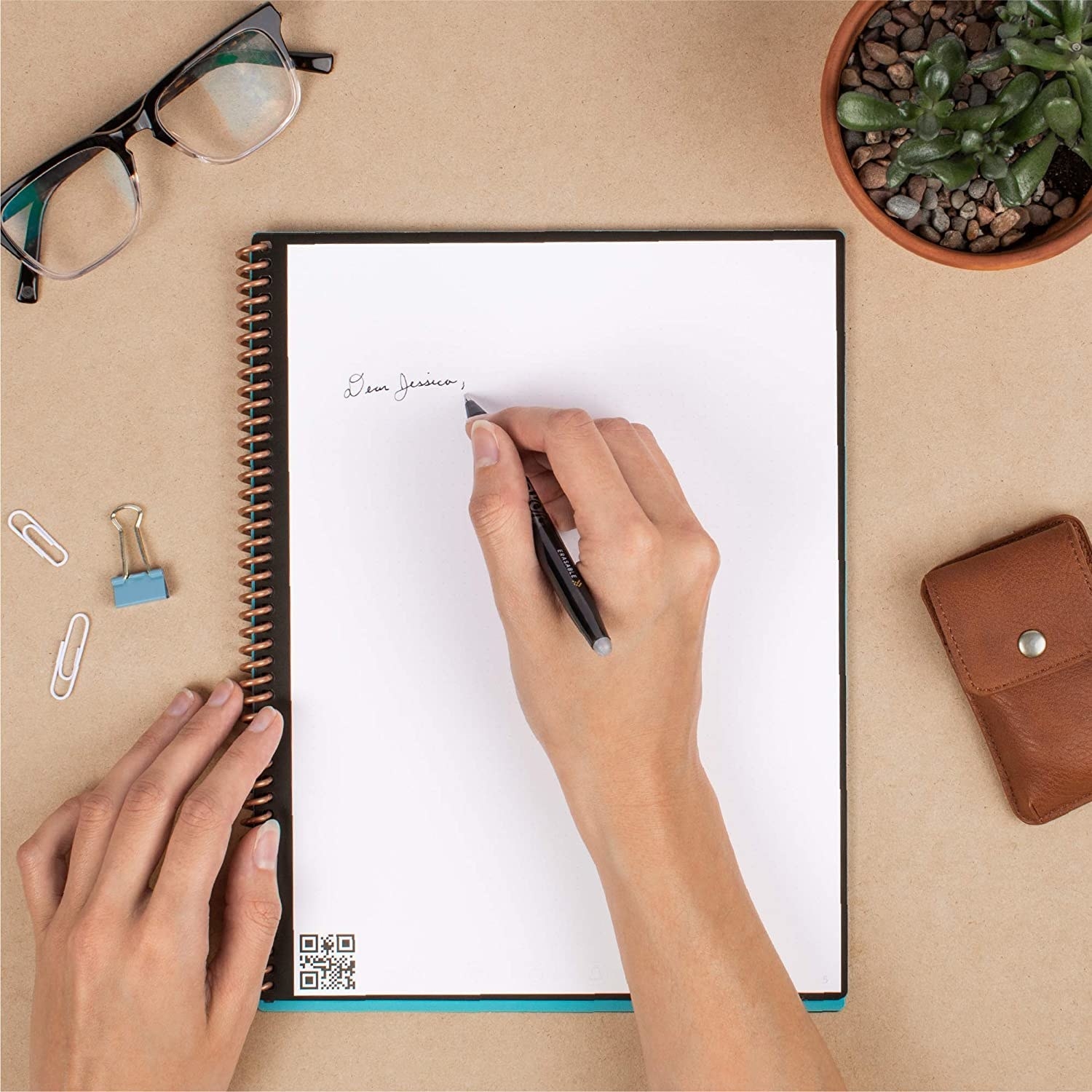 a model writes on a blank page of the reusable spiral bound notebook