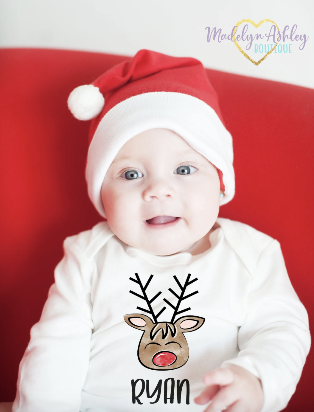 a baby in a white long sleeve bodysuit with a reindeer on it and the name &quot;ryan&quot;