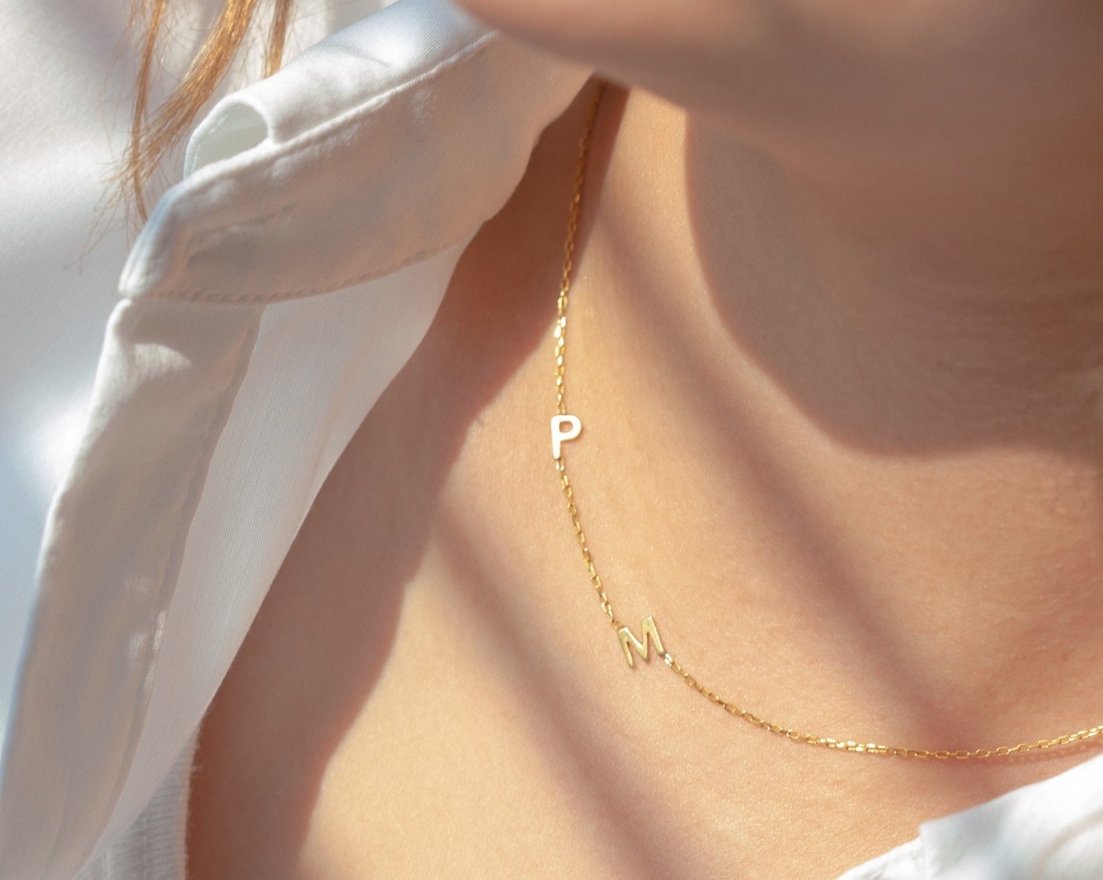 A model wears the gold necklace with the initials P and M attached to it.