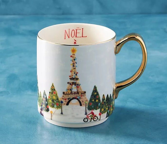 A beautiful coffee mug depicting the Eiffel Tower lit up with Christmas lights and surrounded by snow.