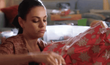 A gif from a bad moms christmas where Mila Kunis is messily wrapping presents