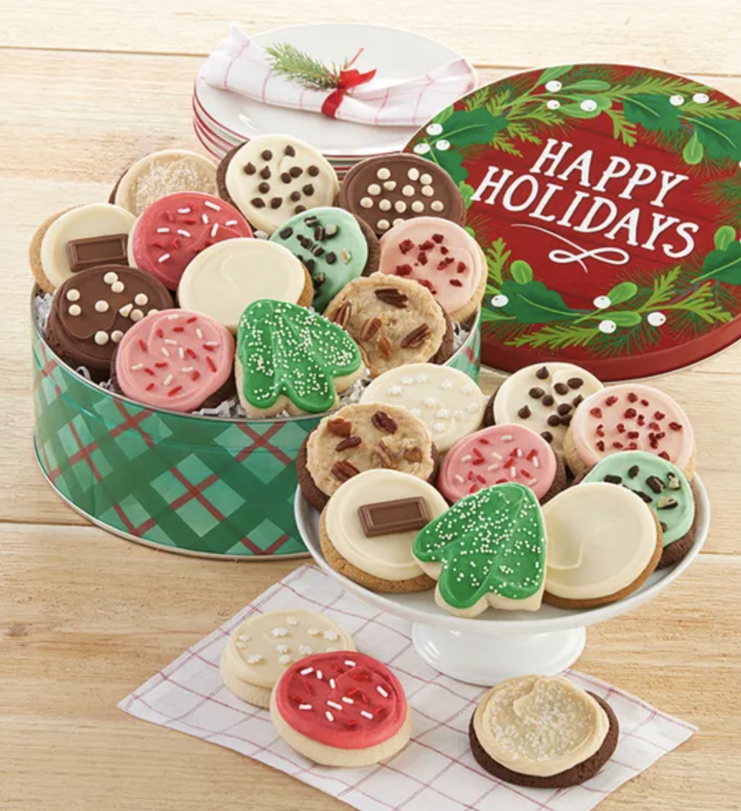 24 cookies with red, white and green frosting sitting in a matching tin that reads &quot;Happy Holidays.&quot;