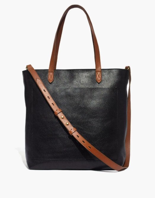 the black tote bag with brown leather handles and a brown crossbody strap
