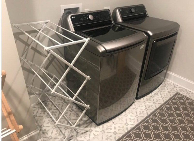A white clothing rack in a reviewers home next to a washer and dryer