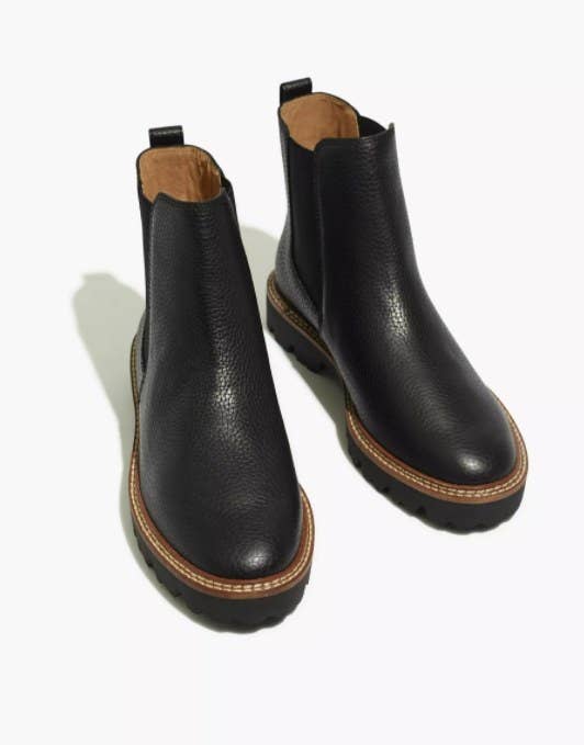 the boots in black with a brown stitched trim around the toe and heel