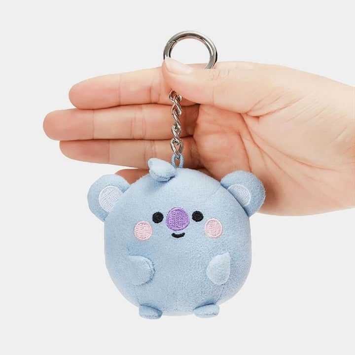 someone holding up a bag clip with a stuffed Koya character on the end