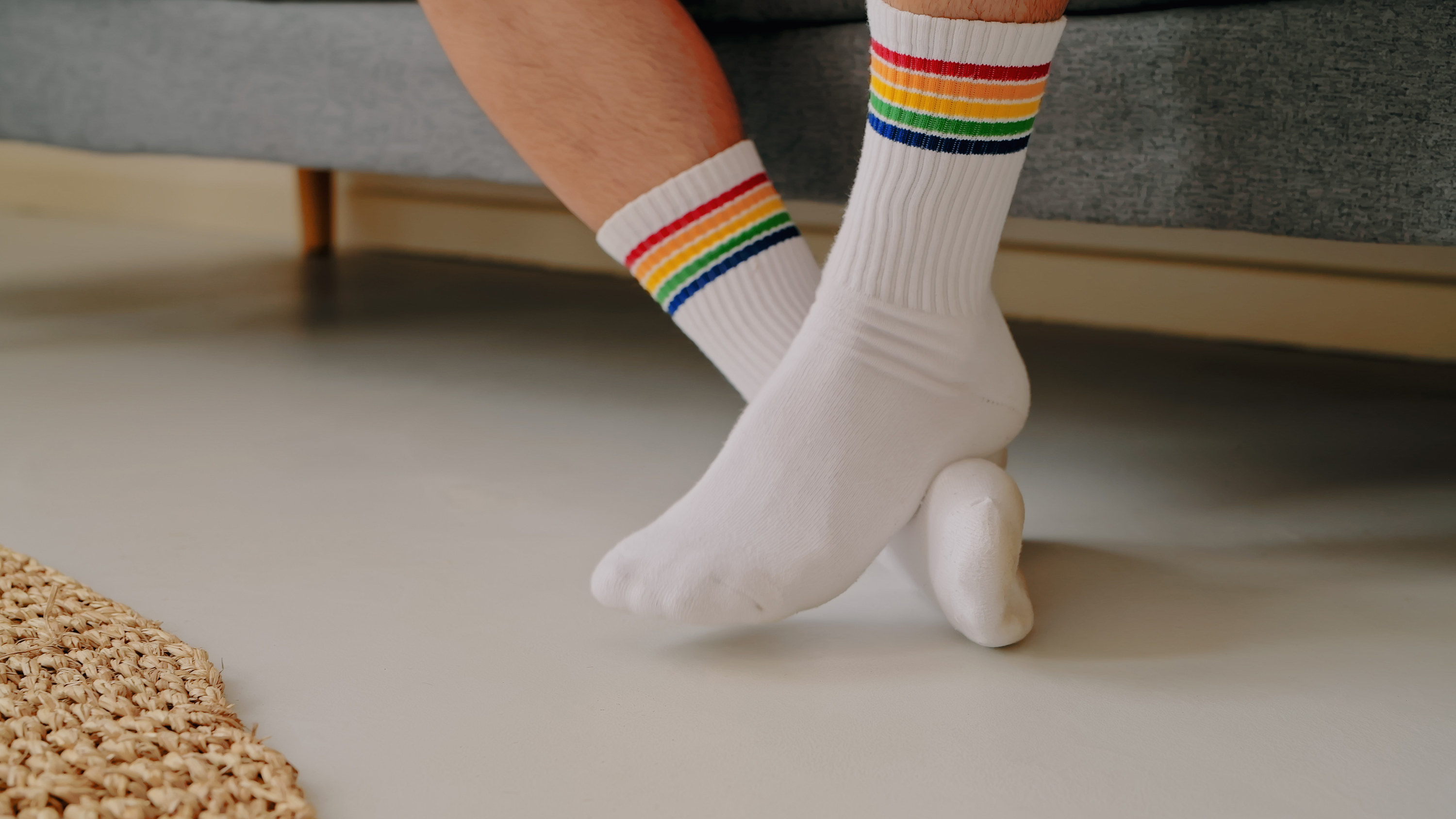 Feet wearing white tube socks with rainbow stripes on them