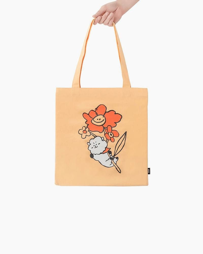 a person holding a canvas bag with a bt21 inspired graphic
