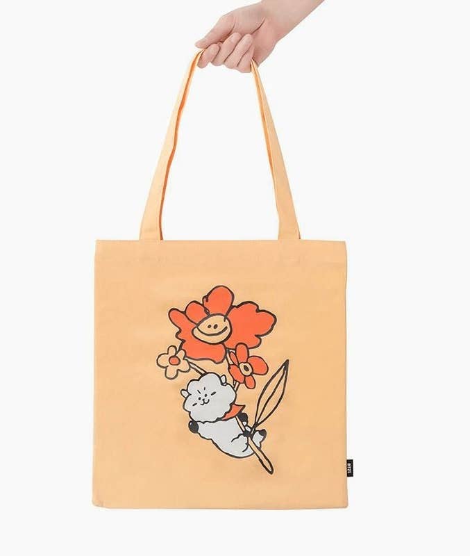 a person holding a canvas bag with a bt21 inspired graphic