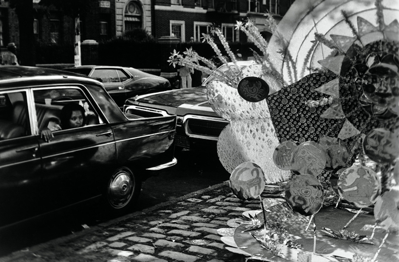 A woman looks out the back of a car window on the street at a colorful scupture