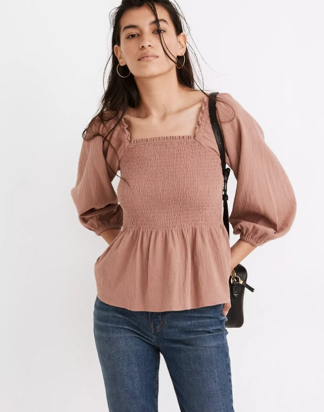 model wearing the top in pink with blue jeans and carrying a black shoulder bag