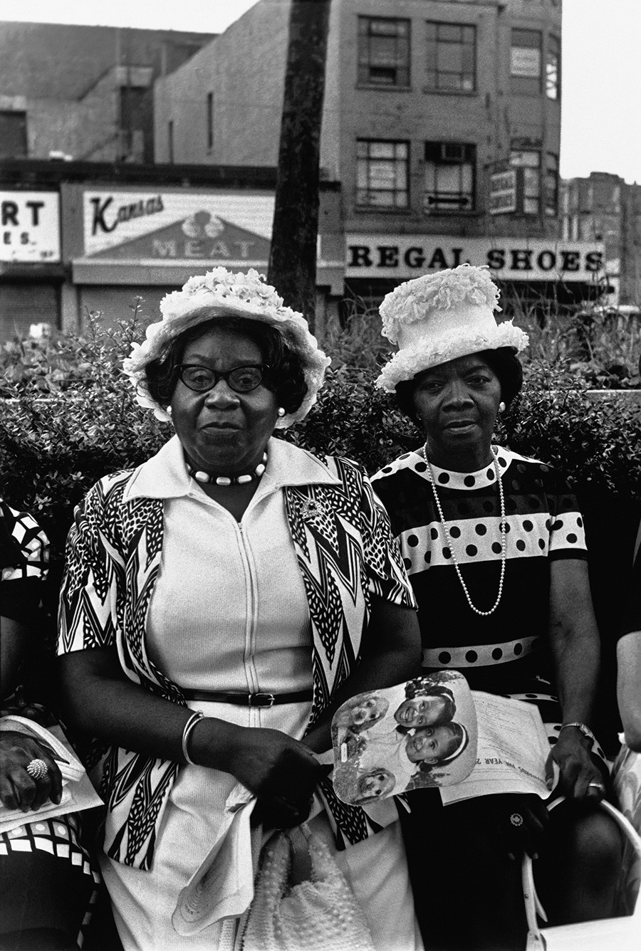 Two older women sitting on a bench smiling looking at the camera