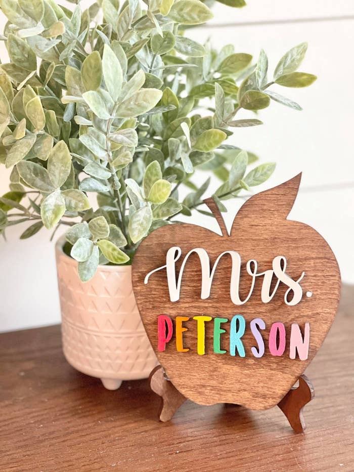 a wooden apple-shaped sign with &quot;mrs. peterson&quot; on it in colorful letters
