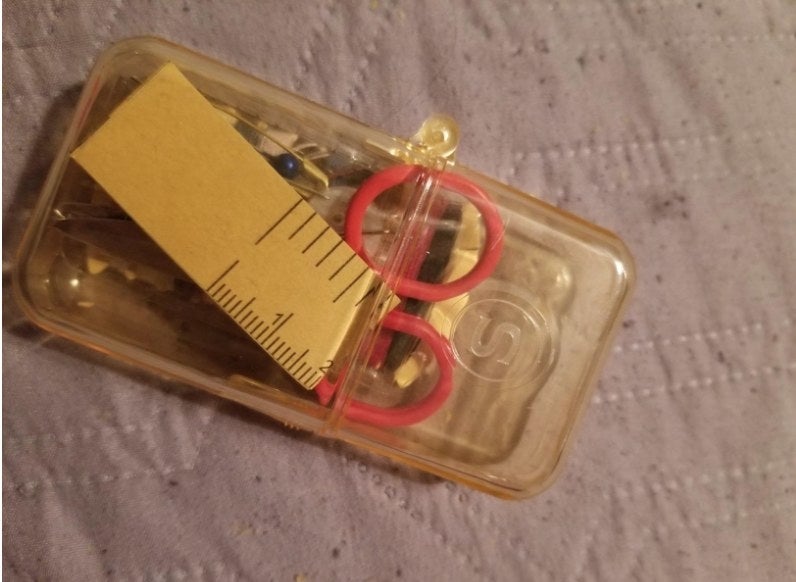 A yellow mini sewing kit on a reviewer&#x27;s purple bed.