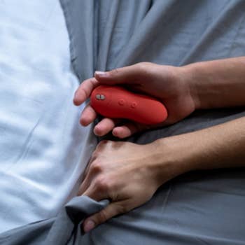 Model holding red palm-sized vibrator and sheet