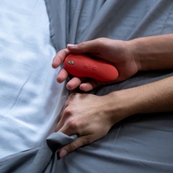 Model holding red palm-sized vibrator and sheet