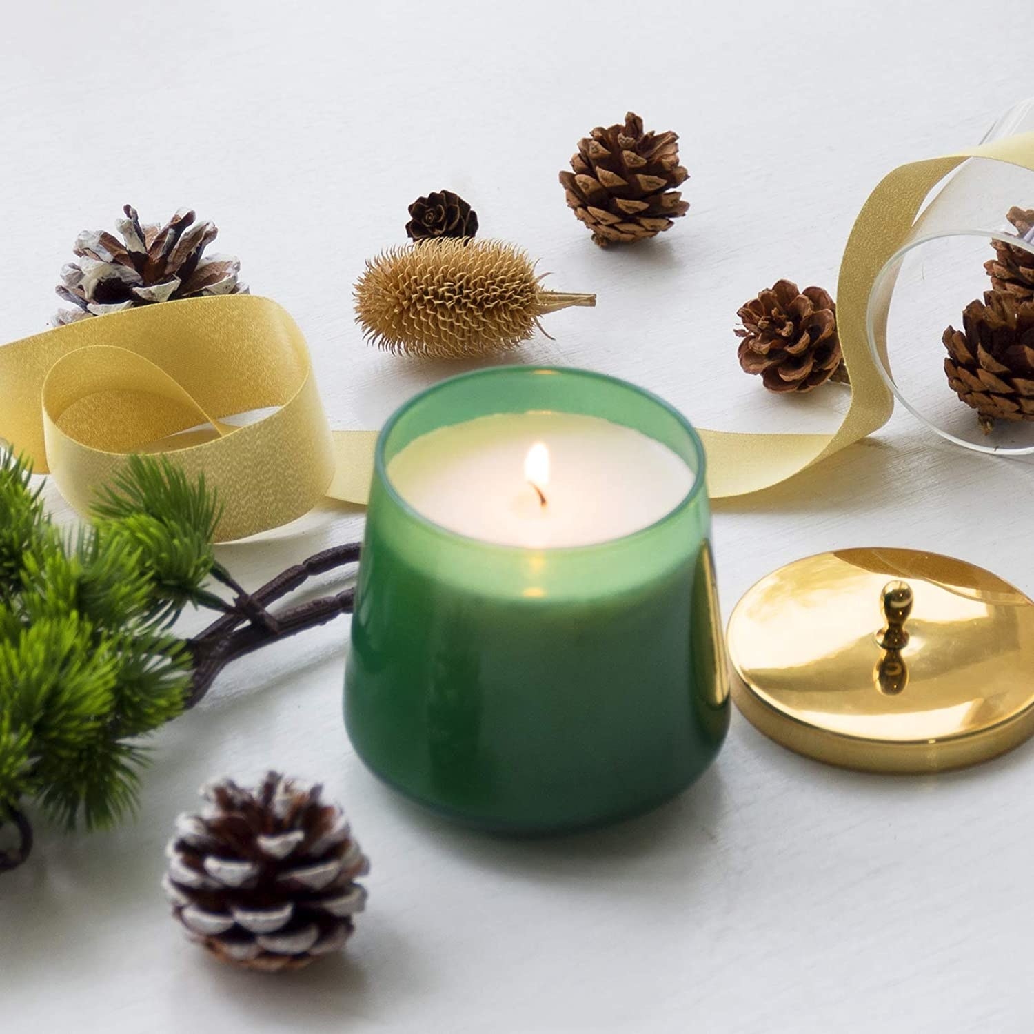 The La Jolie Muse cedar and balsam scented candle surrounded by pinecones and other natural decor