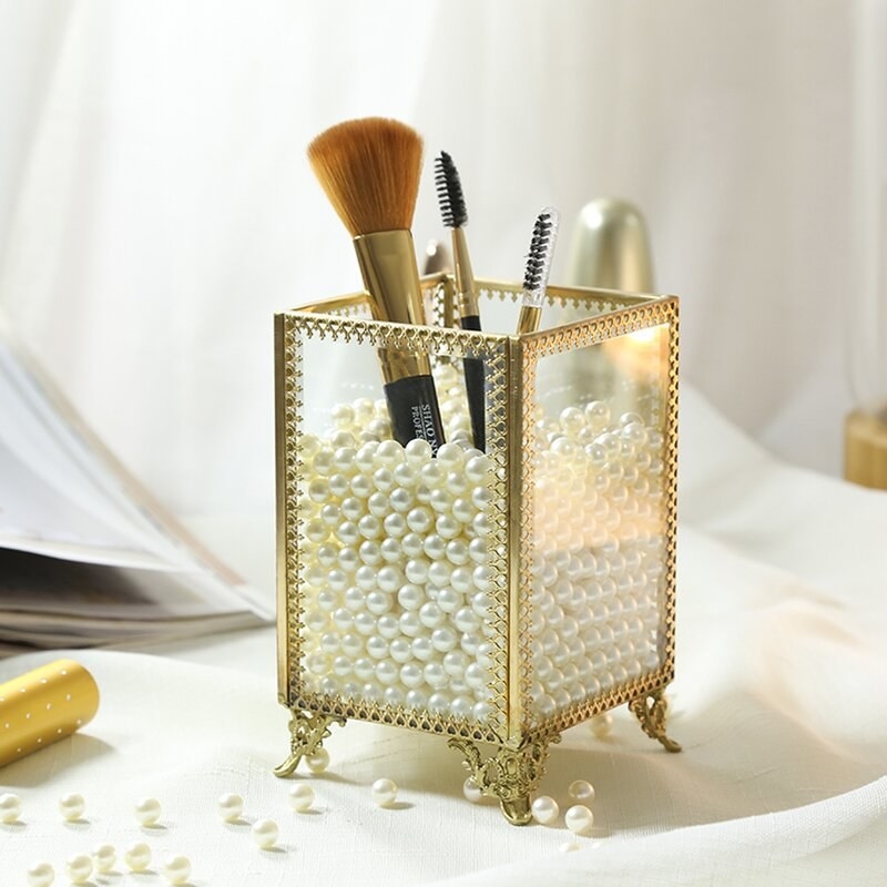 A gold and pearl makeup brush holder