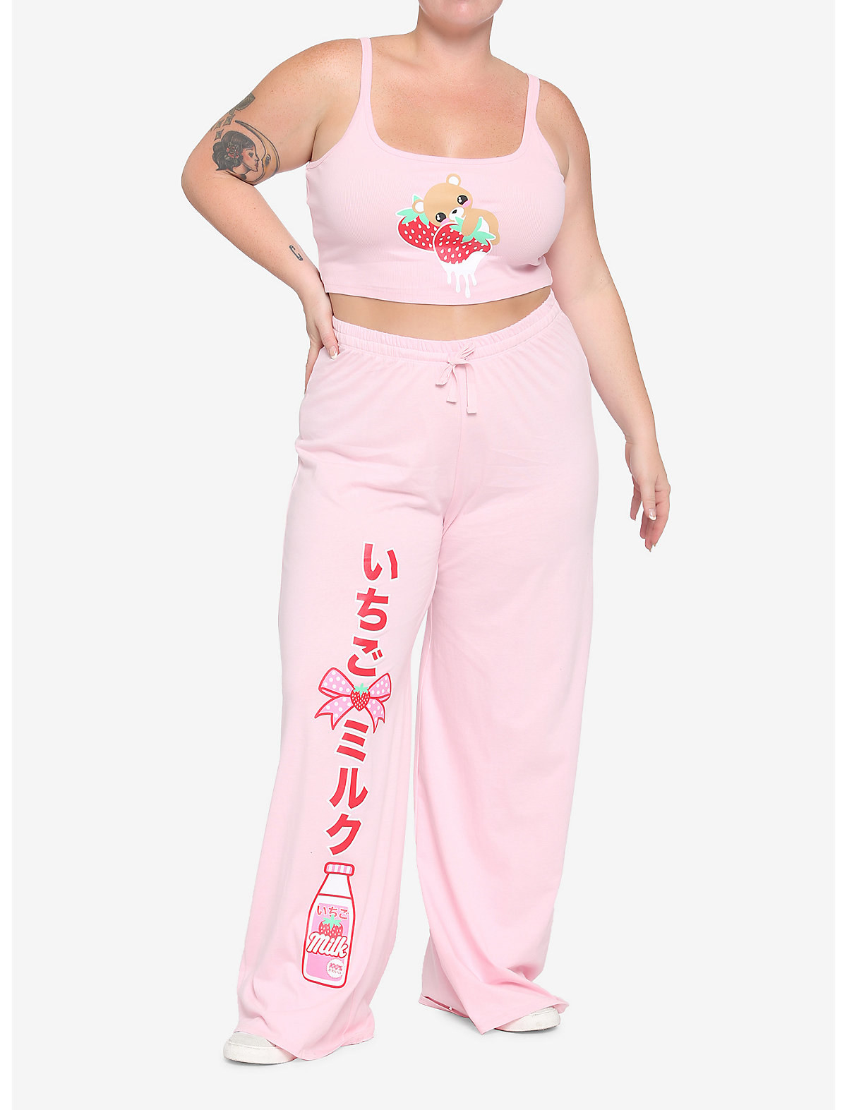 Model is wearing a light pink tank top with a teddy bear and strawberries on it and pink pants that have Japanese writing and strawberry milk