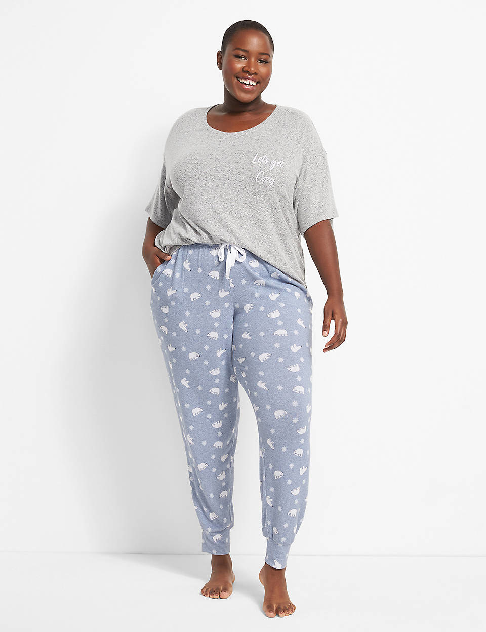 Model is wearing a grey top that says &quot;let&#x27;s get cozy&quot; and pale blue pajama pants with little white polar bears and snowflakes all over it
