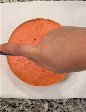 GIF of reviewer using the leveler to evenly slice a cake layer in half