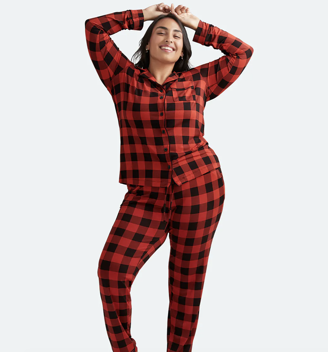 Model is wearing a red and black plaid long sleeve pajama set with pants