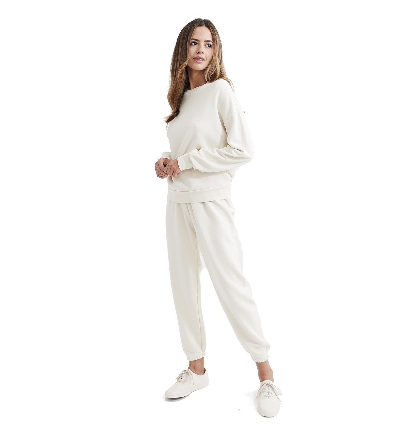 Model is wearing a cream colored sweatshirt and sweat pant set