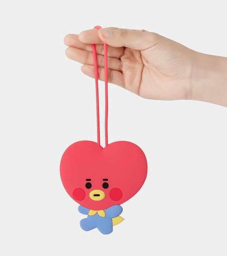 someone holding up a luggage tag shaped like tata one of the bt21 characters