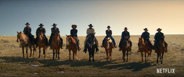 9 gunslingers sitting on their horses look into the camera.