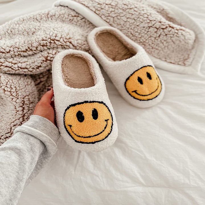 the same reviewer holds up the slippers, showing the tan insole