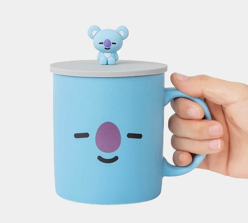 a person holding a lidded mug that&#x27;s shaped like koya, one of the bt21 characters