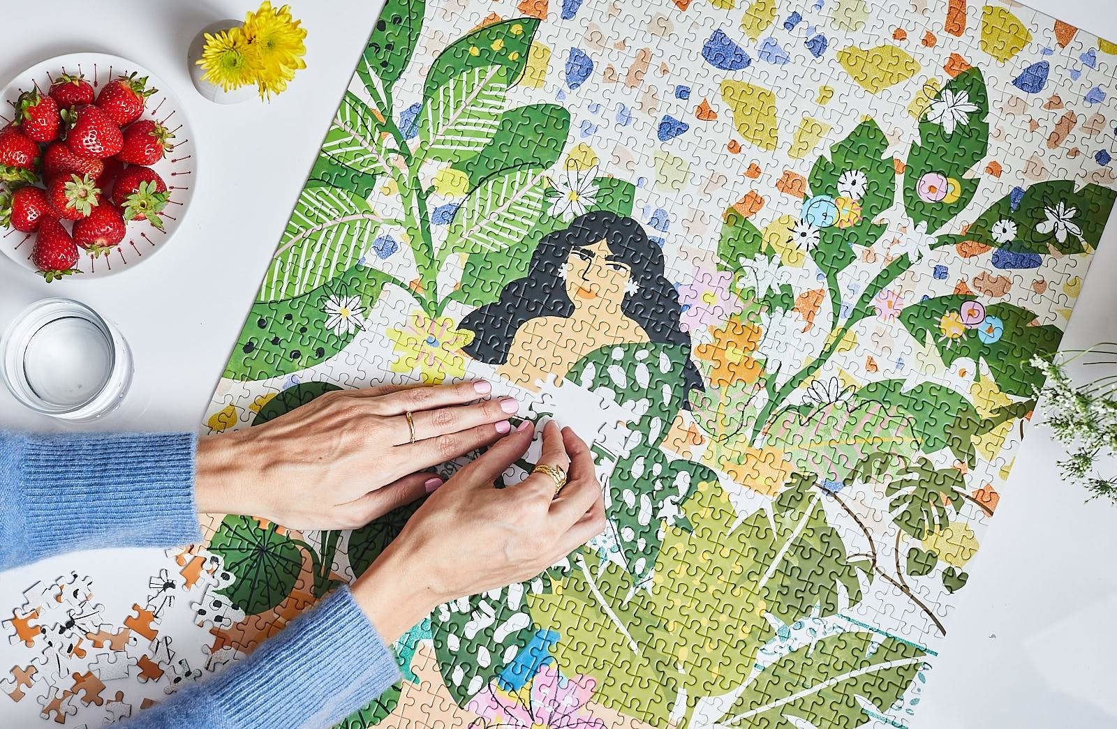 The nearly-completed puzzle "Bathing In Flowers" that shows a woman with dark hair surrounded by greenery and bright flowers.